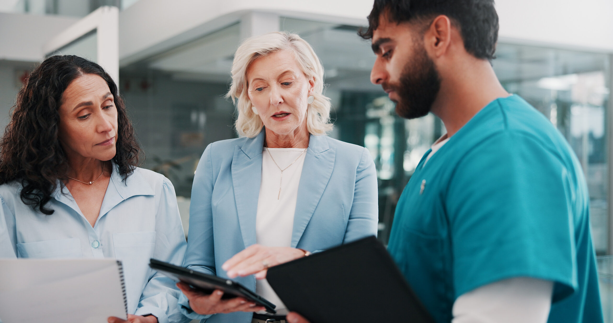 Three healthcare professionals reviewing standard of care documentation and supply planning materials during a clinical trial site discussion.